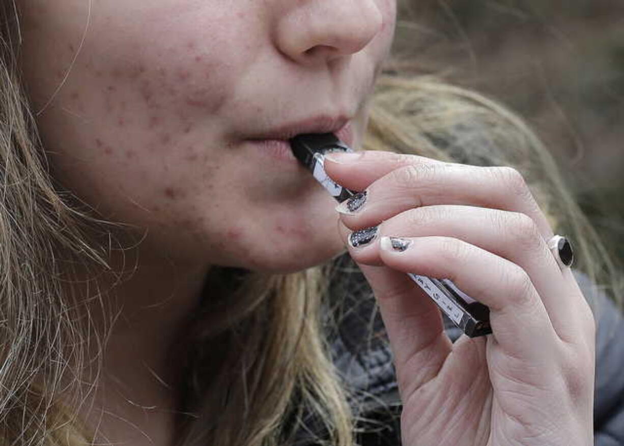 In this April 11, 2018 file photo, a high school student uses a vaping device near a school campus in Cambridge, Mass. A new study released Wednesday, Sept. 18, 2019, found another jump in how many U.S. teens vape nicotine-tinged electronic cigarettes.