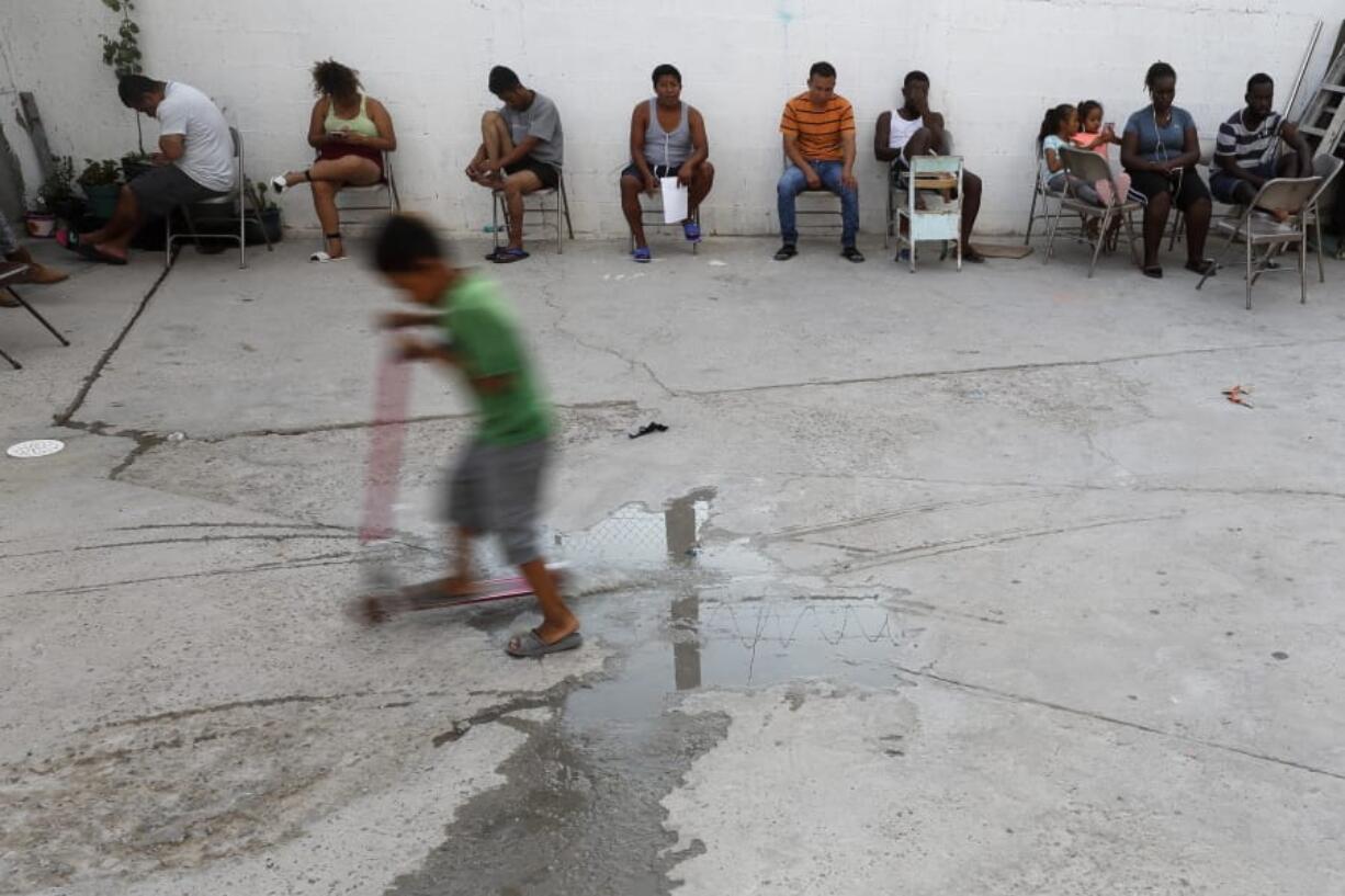 In this July 26, 2019, photo, people from Africa and Central America sit in chairs as the sun sets at El Buen Pastor shelter for migrants in Cuidad Juarez, Mexico.