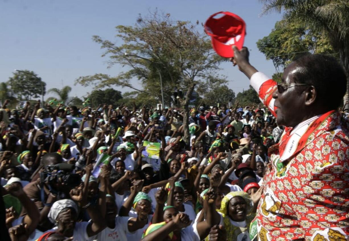 FILE - In this Thursday, June 26, 2008 file photo, Zimbabwe’s President Robert Mugabe, right, greets the crowd at his final rally in Chitungwiza, Zimbabwe. Mugabe, the longtime leader of Zimbabwe who was forced to resign in 2017 after a military takeover, has died at 95.