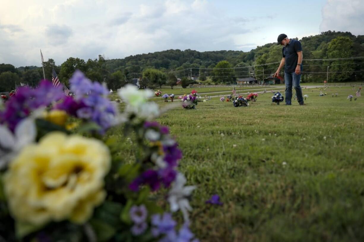 FILE - In this July 17, 2019 file photo, Eddie Davis steps up to the gravestone of his son Jeremy, who died from the abuse of opioids in Coalton, Ohio. While the nation&#039;s attorneys general debate a legal settlement with Purdue Pharma, the opioid epidemic associated with the company&#039;s blockbuster painkiller OxyContin rages on. The drugs still kill tens of thousands of people each year with no end in sight.