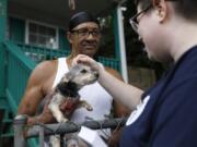 Sylvanus Jackson, left, brings his dog out to meet Lizzy Trawick, a coordinator for LifeLine Animal Project&#039;s Pets for Life program in Atlanta. Trawick visited Jackson&#039;s neighborhood to complete door-to-door outreach for the program, which provides free resources to pet owners in need. Jackson said he has benefited from the program.