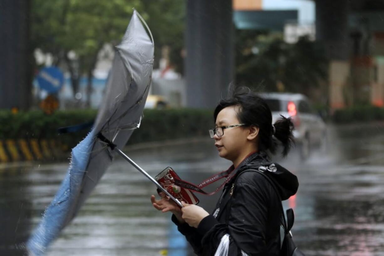 A woman struggles against gusts of wind generated by Typhoon Mitag in Taipei, Taiwan, Monday, Sept. 30, 2019. Fast-moving Typhoon Mitag was bearing down on northern Taiwan on Monday, bringing high winds and heavy rain and forcing flight cancellations.