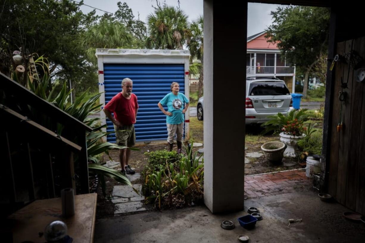 Sandy Cason, center, and her husband David Cason, left, stand outside their home before evacuating as Hurricane Dorian makes its way up the east coast, Wednesday, Sept. 4, 2019, in Tybee Island, Ga. The Casons are still repairing damage from the two previous storms that came close to the coastal barrier island. Sandy Cason said she’s not ready to blame climate change. She noted records show Georgia got hit by several powerful hurricanes in the 1800s. (AP Photo/Stephen B.