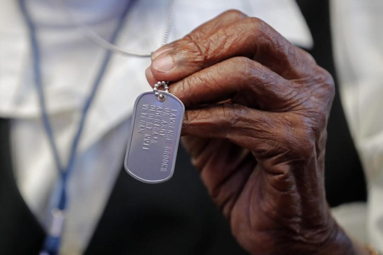 World War II veteran Lawrence Brooks holds a dog tag honoring him as the oldest living World War II veteran, as he celebrates his 110th birthday at the National World War II Museum in New Orleans, Thursday, Sept. 12, 2019. Brooks was born Sept. 12, 1909, and served in the predominantly African-American 91st Engineer Battalion, which was stationed in New Guinea and then the Philippines during World War II. He was a servant to three white officers in his battalion.