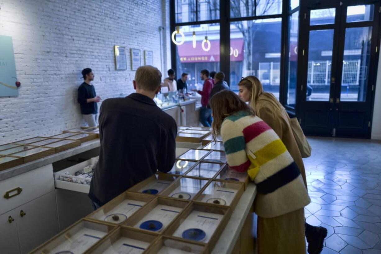 In this Thursday, Feb. 7, 2019, file photo, a bud tender helps customers at a dispensary in Portland, Ore. In the wake of lung illnesses and deaths related to vaping, Oregon will ask its legal marijuana retailers to review the cannabis products on their shelves and voluntarily hold or pull those that they don’t feel confident about.