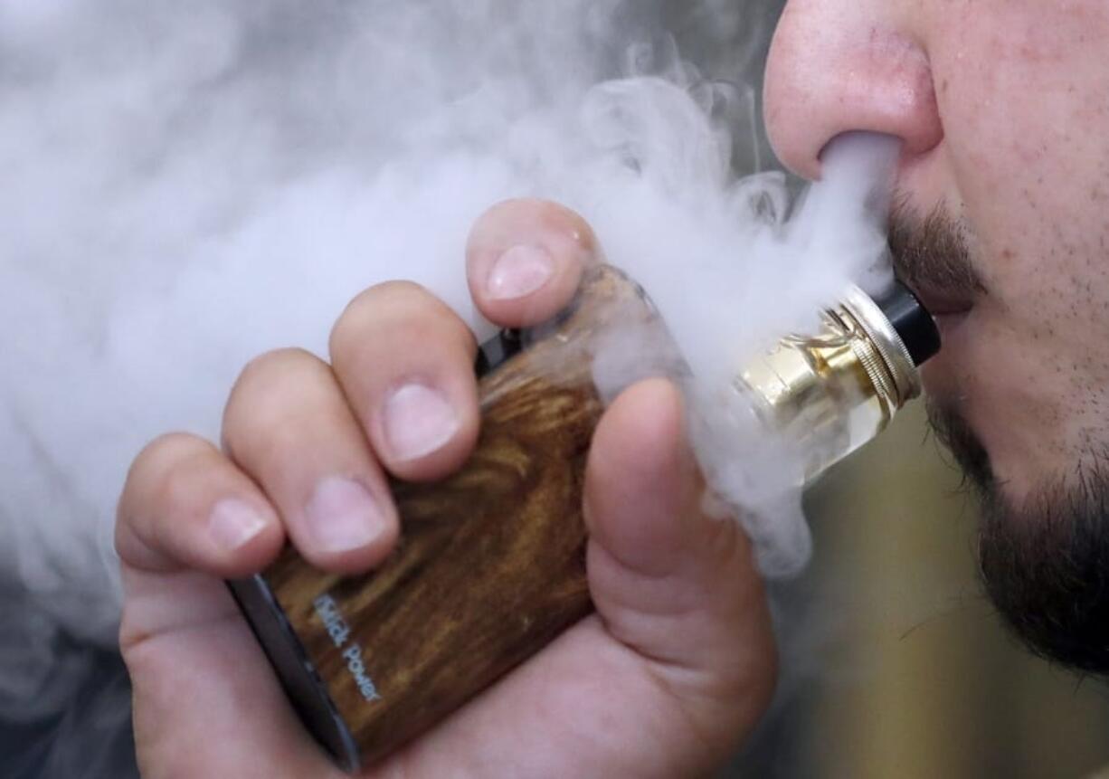 A man breathes vapors from an e-cigarette at a vape shop in London.