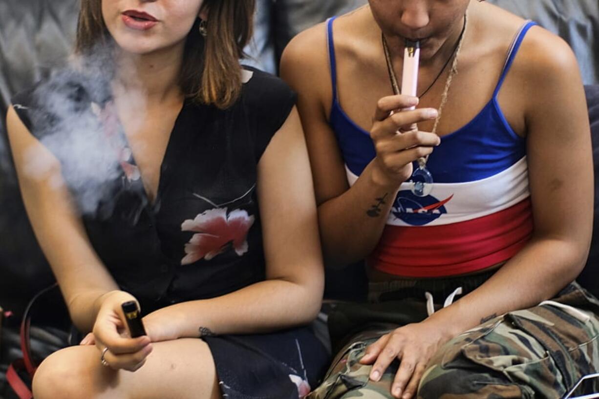 FILE - In this Saturday, June 8, 2019 file photo, two women smoke cannabis vape pens at a party in Los Angeles. On Friday, Sept. 27, 2019, the Centers for Disease Control and Prevention said more than three-quarters of the 805 confirmed and probable illnesses from vaping involved THC, the ingredient that produces a high in marijuana.