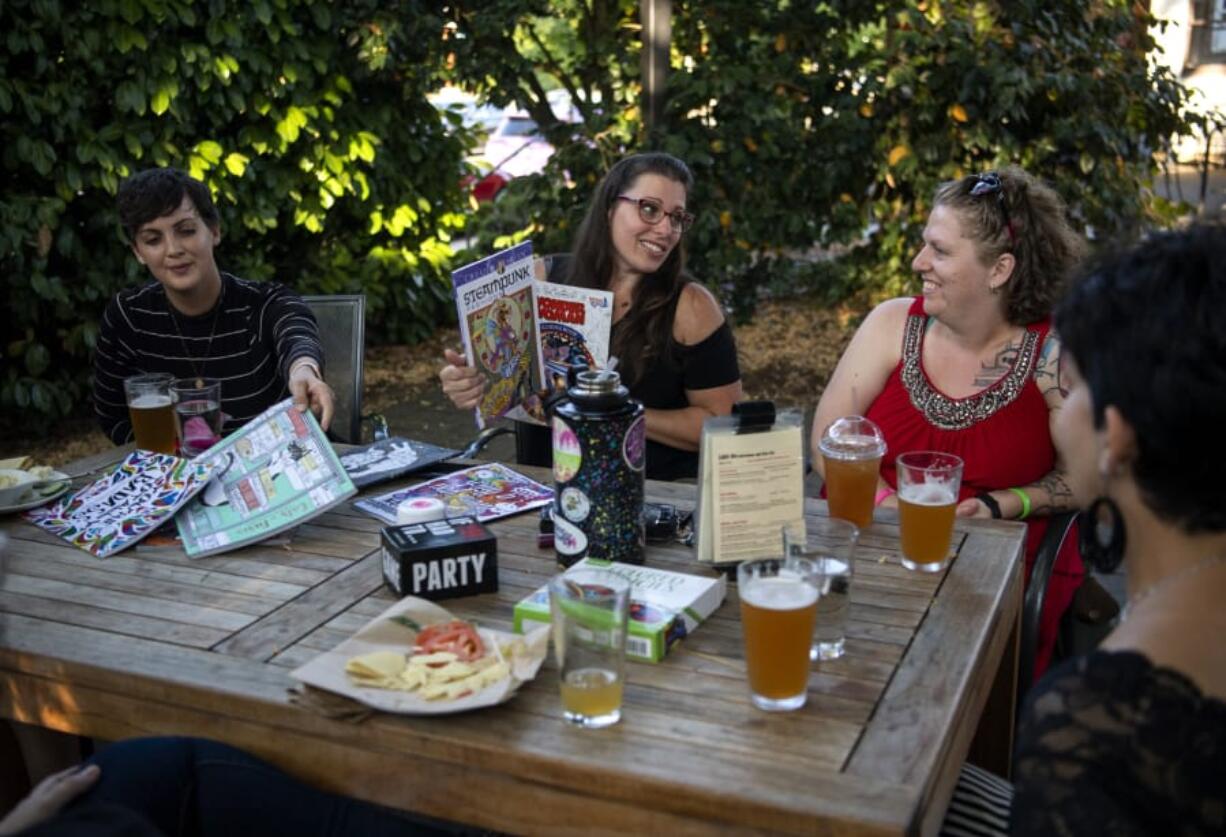 Jana Cox, from left, Adrienne San Nicolas and Erin Maher pick out adult-themed coloring books to work on during the first meeting of a new group for young breast cancer survivors organized by Pink Lemonade Project. The group aims to serve women who don&#039;t identify with mainstream outreach efforts.