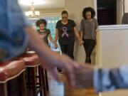 Family friend Zahira Cooper, 9, from left, Zsaneen Kennedy and her daughter LaQuay Kennedy pray before dinner. The family often gathers for dinner. Kennedy said she is concerned about her daughters getting breast cancer, which runs in the family.