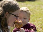 Jessica Peters takes a bite of a caramel apple offered by her 4-year-old son, Calvin, during Saturday&#039;s Old Apple Tree Festival at Vancouver&#039;s Old Apple Tree Park.