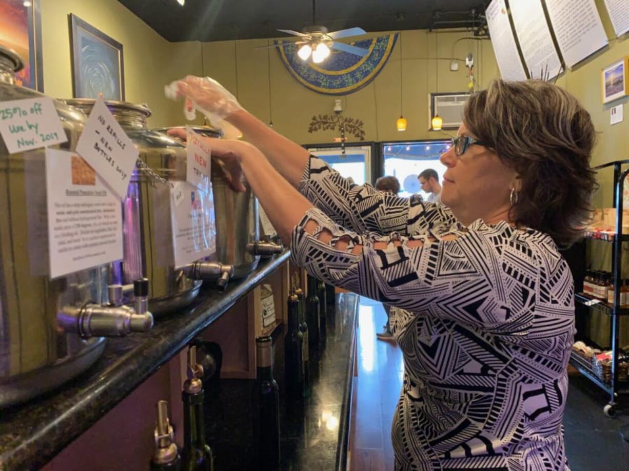 Gabby Navidi of Navidi&#039;s Olive Oils and Vinegars refills a bottle of olive oil.