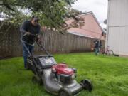 Charlie White with Thomason Landscaping Company mows the grass in the backyard of an Orchards house.