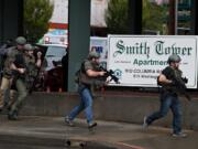 Law enforcement officers rush into Smith Tower Apartments after an active shooter opened fire in downtown Vancouver on Thursday afternoon, Oct. 3, 2019.