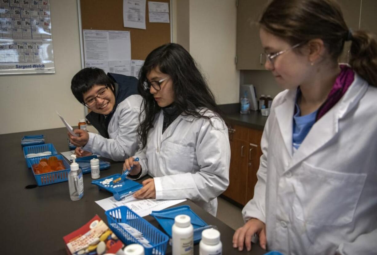 Henrietta Lacks Health and Bioscience High School seniors Dante Diaz, from left, Paola Terrazas and Anastasiya Kashyrna demonstrate how they learn how to count medication in their pharmacology classroom. The classrooms use pretend medicine, like cornstarch pills, or even beans and beads to mimic medication. Henrietta Lacks High offers programs in biotechnology, biomedical engineering, public health, pharmacy, nursing and patient services.