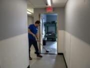 Dean Cardiff, engagement specialist with Share House, cleans the newly replaced floors Monday afternoon shortly before residents were set to return to the shelter. The men's homeless shelter reopened Monday evening after nine weeks of being closed to repair fire and water damage.