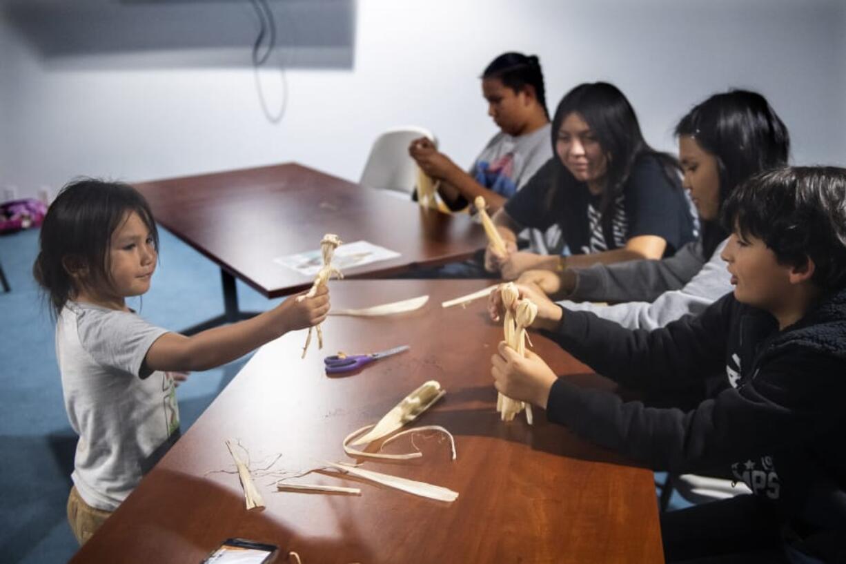 Roberto Ruiz, 4, left, shows off his cornhusk doll to Christian Knack, 9, right, during a potluck at the Cowlitz Indian Tribe building in Hazel Dell on Monday night. The Native American Parent Association of Southwest Washington is trying to revitalize a program for Native American students after area school districts stopped participating in the Title VI Native American Indian Education Program.