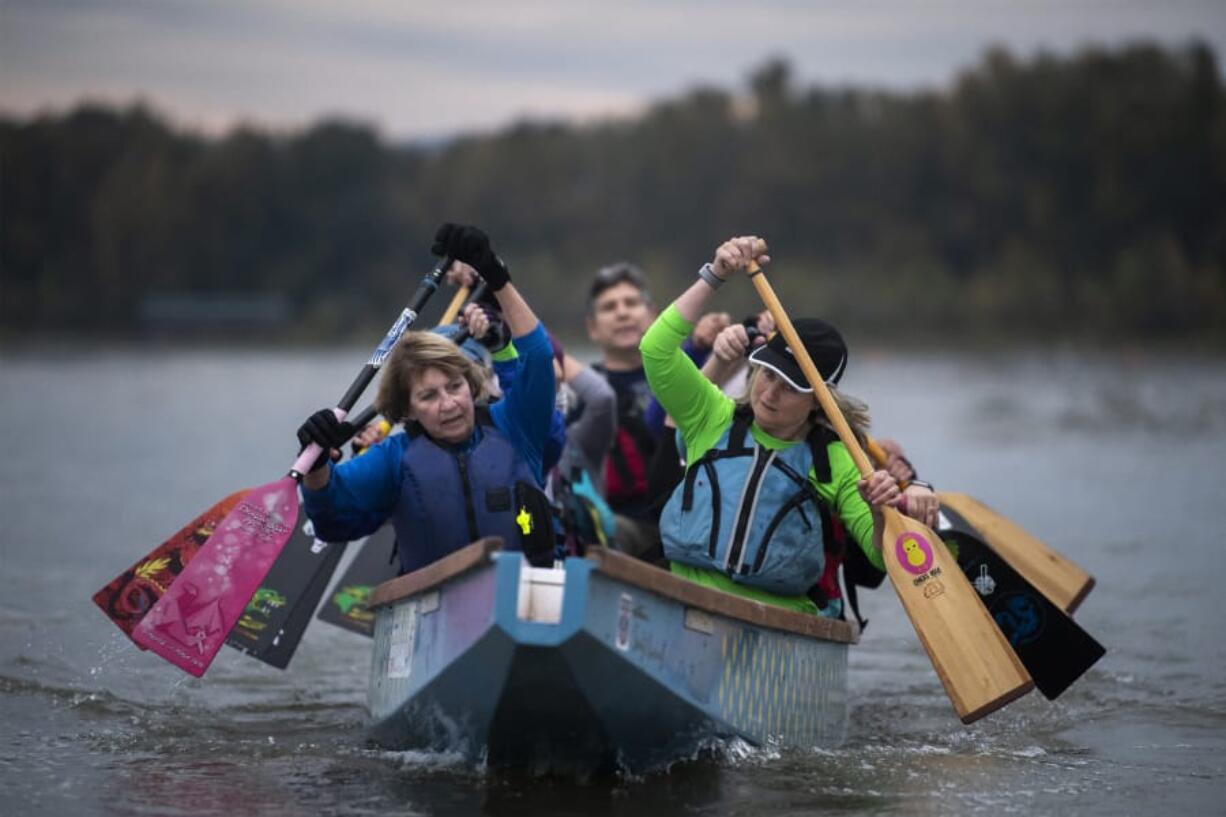 Paula Zellers, left, and Laura Thornquist row at the front of their team's dragon boat on Vancouver Lake. Their team, Catch-22, which is coed and has about 75 members, features close to a dozen people diagnosed with breast cancer. Zellers and Thornquist are two of those people.