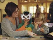 Max Hoskins, 5, center, shows off his bat mask while reading a book with Rowena Hoskins, left, and Opal Hoskins, 3, right. The Hoskins were among the attendees at the Vancouver Water Resources Education Center's "Creatures of the Night" event on Saturday.