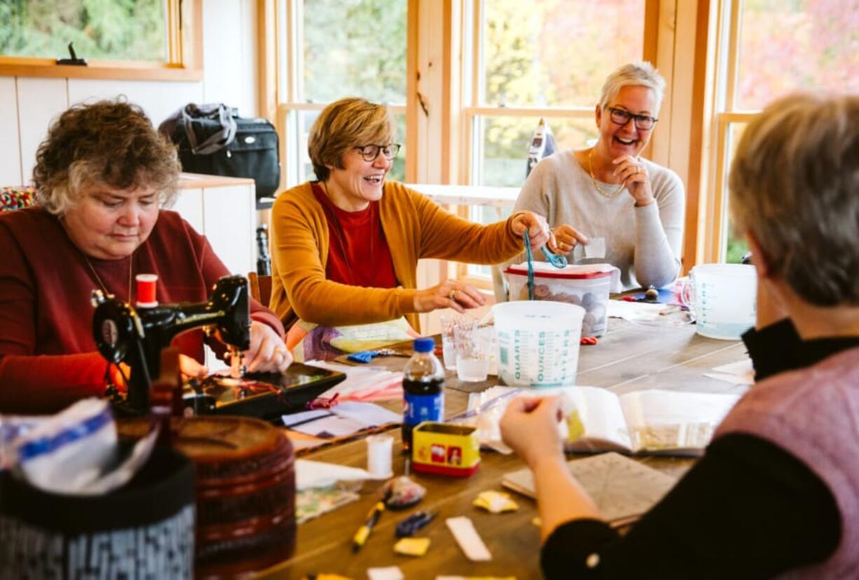 Julie Reese of Michigan, from left, Deb Spofford of North Salmon Creek and Jenny Mooijman of the Netherlands joke together with other friends during a reunion of their quilting group hosted by Spofford on Sunday.