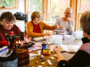 Julie Reese of Michigan, from left, Deb Spofford of North Salmon Creek and Jenny Mooijman of the Netherlands joke together with other friends during a reunion of their quilting group hosted by Spofford on Sunday.