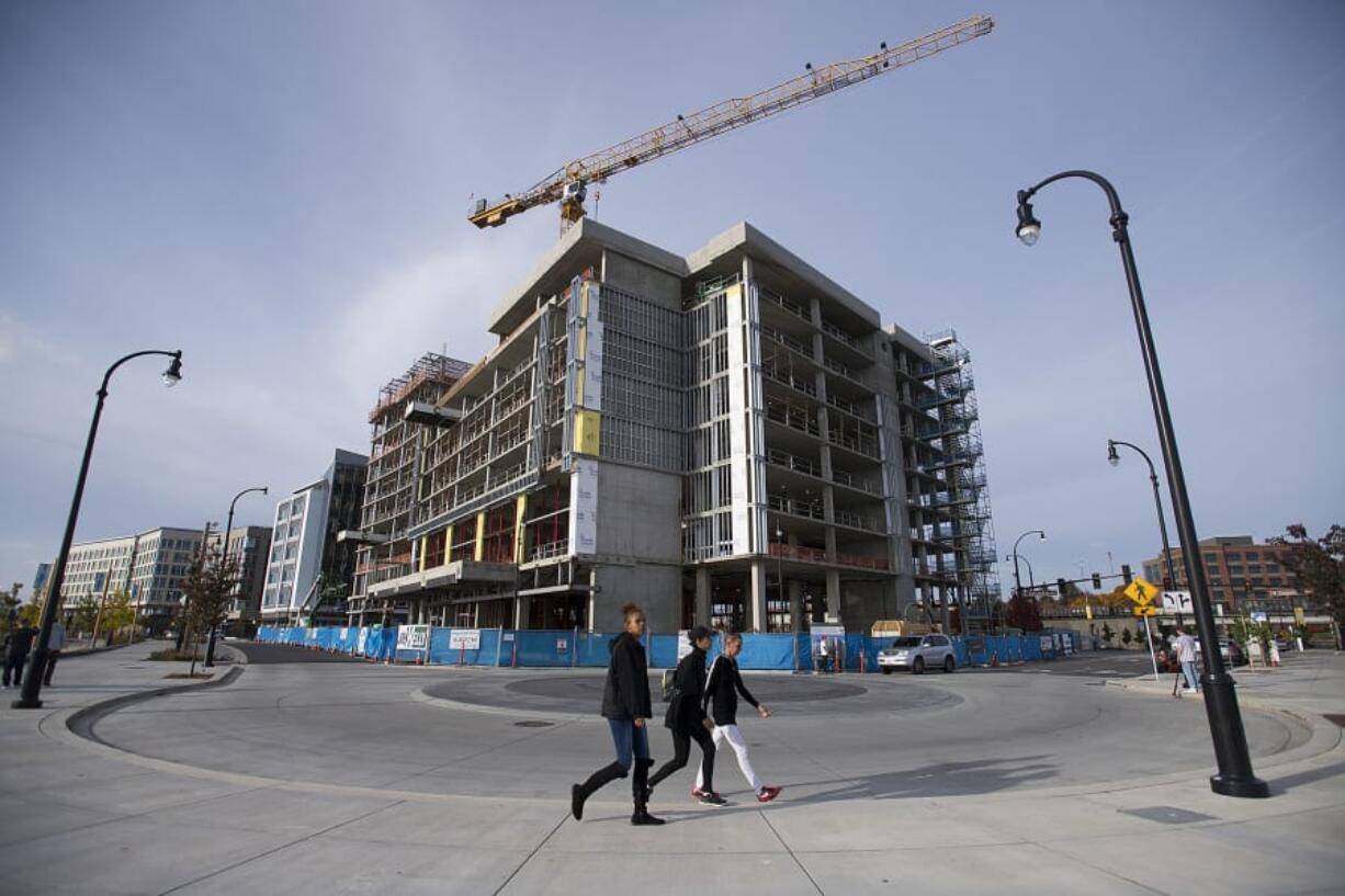 Vancouver residents Allie Thompson, from left, and Ebony Thompson join their mom, Angel Thompson, as they stroll past the crane for the Kirkland Tower and Hotel Indigo, which are still under construction.