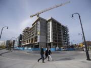 Vancouver residents Allie Thompson, from left, and Ebony Thompson join their mom, Angel Thompson, as they stroll past the crane for the Kirkland Tower and Hotel Indigo, which are still under construction.