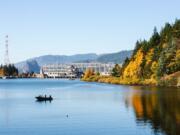 Two people in a lone boat fish upstream of Bonneville Dam off Bradford Island, seen to the right. The Yakama Nation along with the states of Washington and Oregon this month requested the U.S. Environmental Protection Agency designate the area as a Superfund site.