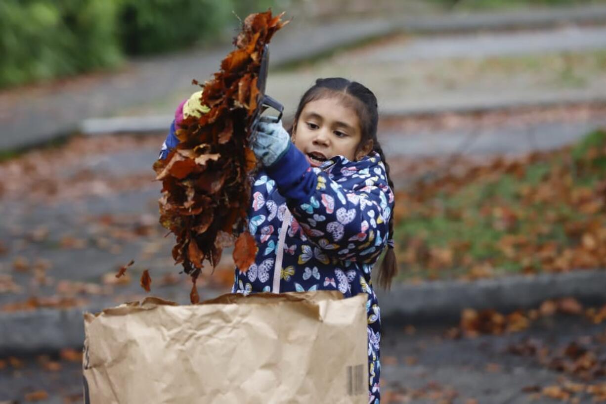 Bella Yeakle, 8, picks up leaves at the Uptown Village cleanup on Saturday. The cleanup effort was part of Make a Difference Day, an annual initiative encouraging community members to participate in a community service project.