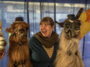 Jamie Jefferson of Portland poses Sunday with llamas Rojo, left, and Smokey, right, in Portland's Pioneer Courthouse Square during a celebration of Rojo's retirement after 12 years of celebrity and service.