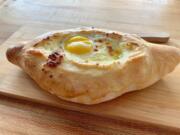 Khachapuri adjaruli (bread topped with melted cheese, butter and egg) at Dediko.