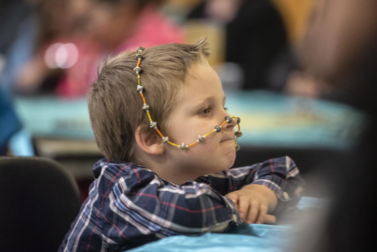 Henry, 5, who's mother declined to provide a last name, plays with a necklace of beads during the celebration of the 200th anniversary of the birth of the Bab at the Water Resources Education Center on Monday night, Oct. 28, 2019.