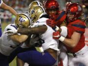 Washington running back Salvon Ahmed, middle, gets pushed into the endzone for a touchdown against Washington in the second half during an NCAA college football game, Saturday, Oct. 12, 2019, in Tucson, Ariz.