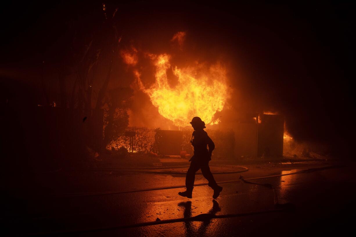 Firefighters try to save a home on Tigertail Road during the Getty Fire, Monday, Oct. 28, 2019, in Los Angeles, Calif.