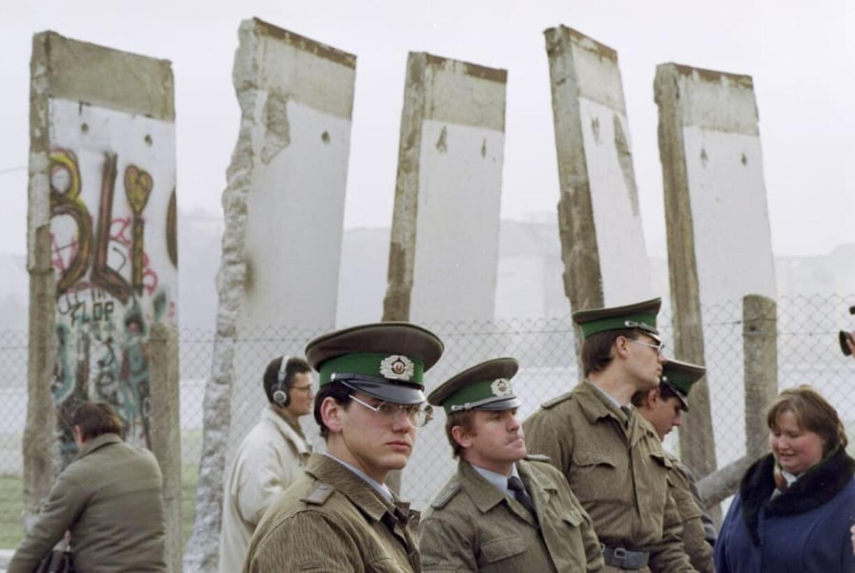 FILE - In this Monday, Nov. 13, 1989 file photo, East German border guards stand in front of segments of the Berlin Wall, which were removed to open the wall at Potsdamer Platz passage in Berlin. When the Berlin Wall fell, the Soviet Union stepped back, letting East Germany&#039;s communist government collapse and then quickly accepting German unification.