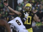 Oregon quarterback Justin Herbert, right, passes under pressure from California&#039;s Kuony Deng during the second quarter of an NCAA college football game Saturday, Oct.. 5, 2019, in Eugene, Ore.