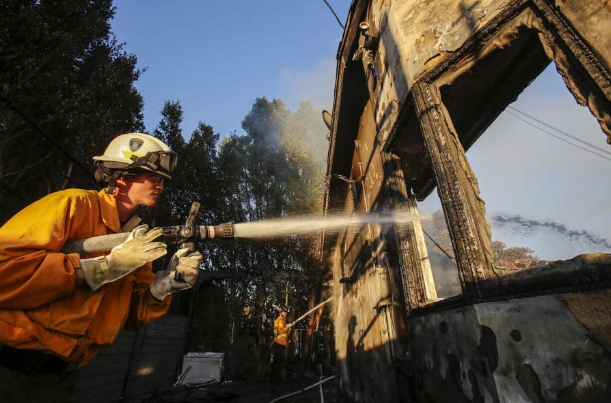 Firefighters work on a house destroyed by a wildfire called the Getty Fire in Los Angeles, Monday, Oct. 28, 2019. (AP Photo/Ringo H.W.