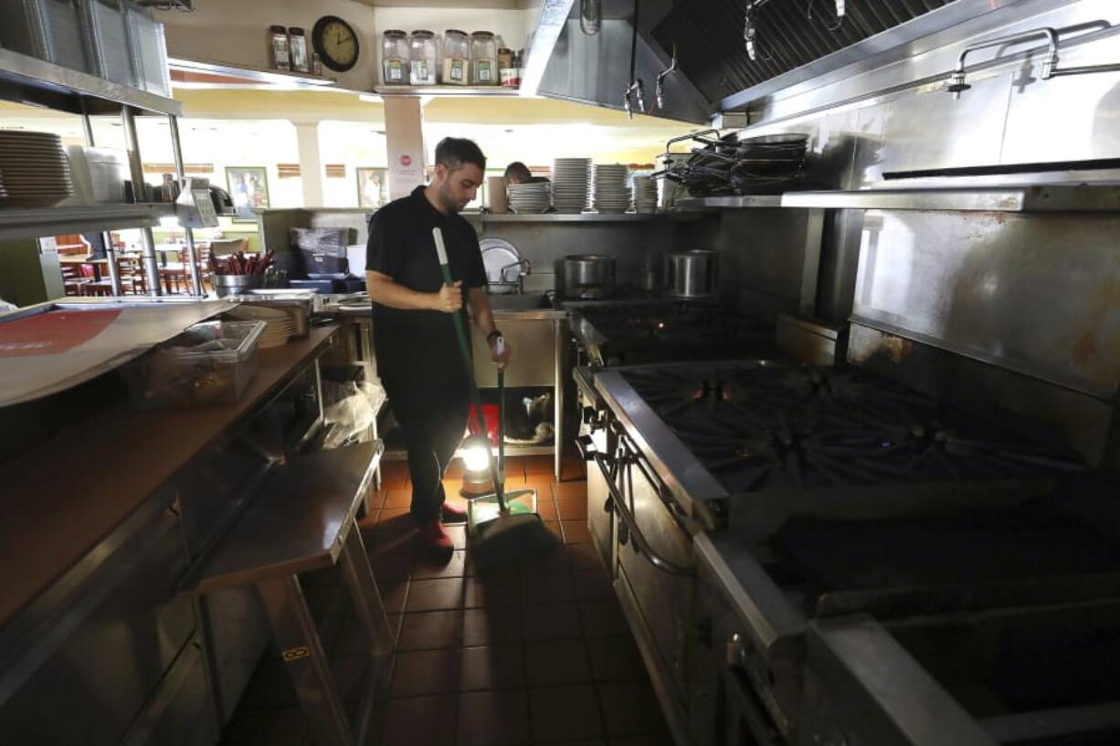 Salvador Espinosa sweeps in the kitchen of a Mary&#039;s Pizza Shack restaurant during a Pacific Gas and Electric Co. power shutdown in Santa Rosa, Calif., Thursday, Oct. 10, 2019. More than 1.5 million people in Northern California were in the dark Thursday, most for a second day, after the state&#039;s biggest utility shut off electricity to many areas to prevent its equipment from sparking wildfires as strong winds sweep through the region.