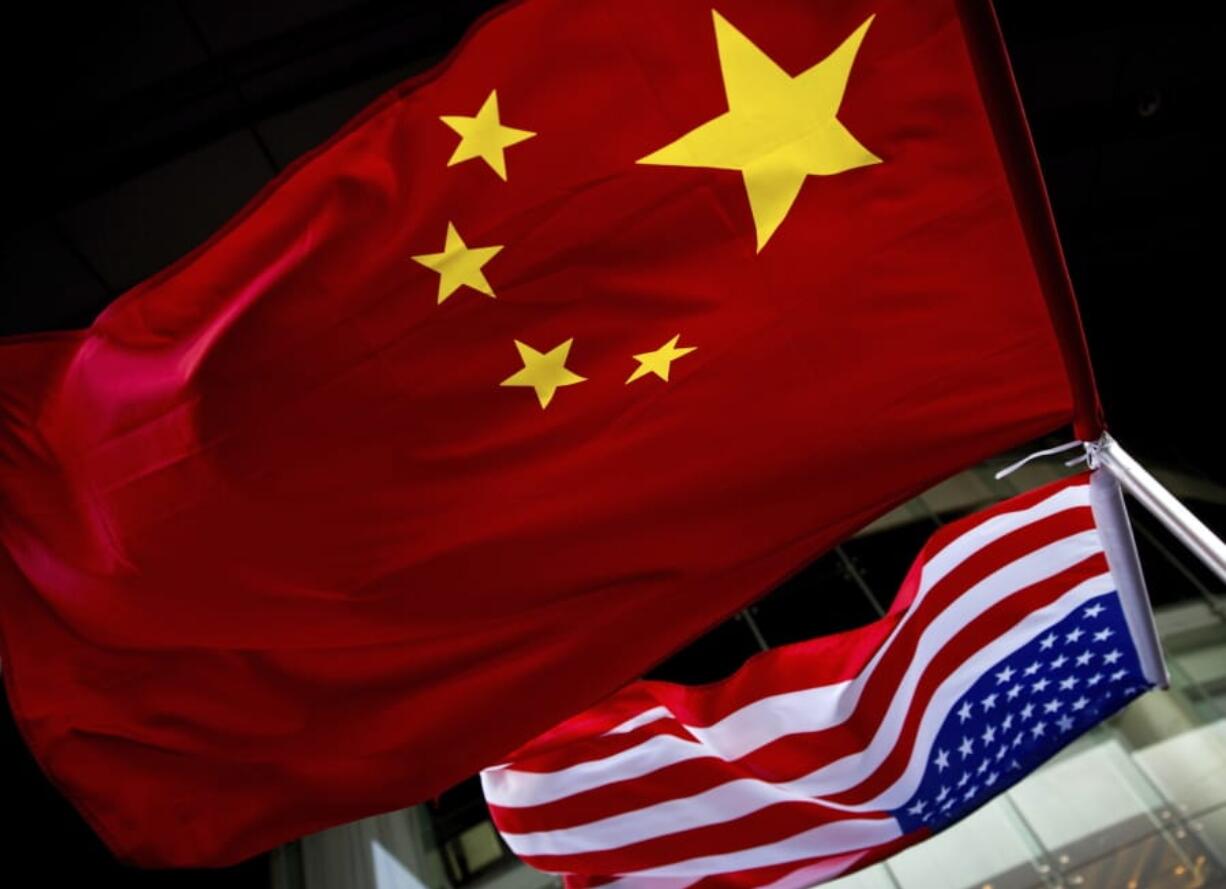 In this Nov. 7, 2012 photo, U.S. and Chinese national flags are hung outside a hotel during the U.S. Presidential election event, organized by the U.S. embassy in Beijing. Government-linked Chinese hackers have intercepted the text messages of thousands of foreigners by penetrating a telecommunications provider and planting eavesdropping software on its servers, the cybersecurity firm FireEye says.