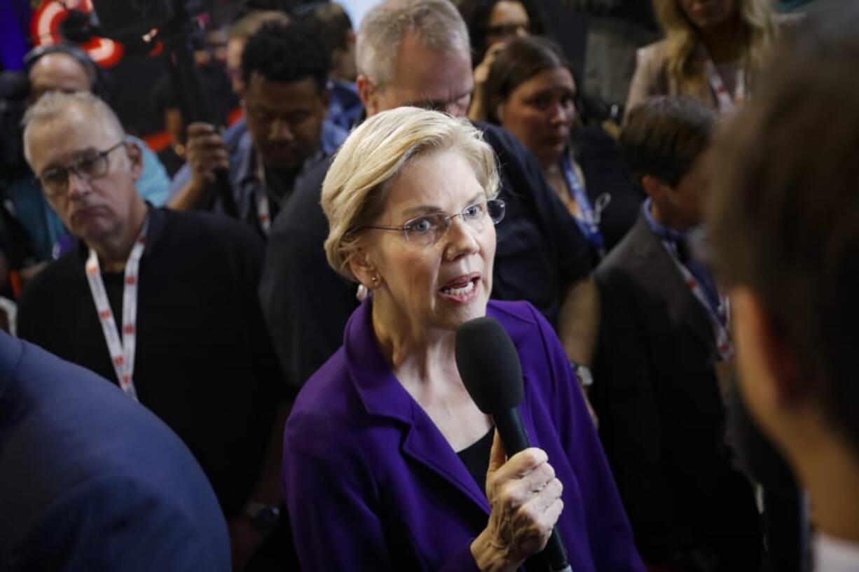 In this Oct. 15, 2019, photo, Democratic presidential candidate Sen. Elizabeth Warren, D-Mass., speaks in the spin room following a Democratic presidential primary debate at Otterbein University in Westerville, Ohio. The Democratic presidential candidates are not talking much about impeachment as they campaign.