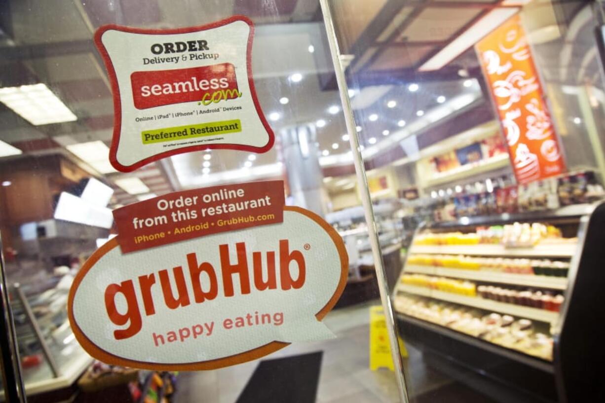 FILE - This April 4, 2014 file photo shows signage for food delivery services GrubHub and Seamless displayed on the door of a restaurant in New York. The growing options for outsourcing meal planning, grocery shopping and cooking can be called time-saving blessings or culture-destroying curses. In the end, they&#039;re probably a complicated mix of both.