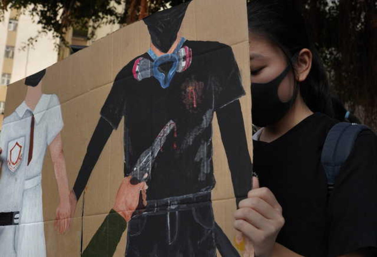 A supporter raises a printing featuring a protester shot in the chest by police during a strike in Hong Kong, Wednesday, Oct. 2, 2019. Hundreds of students at a Hong Kong college have staged a strike to condemn police shooting of a teenager during widespread violence in the semi-autonomous Chinese territory at pre-democracy protests that marred China's National Day.