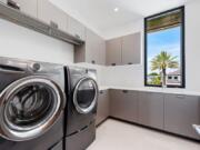 This photo provided by interior designer Raquel Mothe of Mothe Design shows a laundry room designed by Mothe in Fort Lauderdale, Fla. This laundry room includes plenty of storage with cabinets by Ornare, as well as recessed ceiling lighting and natural light, creating a space that&#039;s welcoming and also functional.