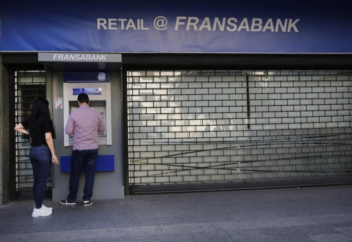 People use ATM outside a closed bank, in Beirut, Lebanon, Wednesday, Oct. 30, 2019. Lebanese banks have been closed for the last two weeks as the government grapples with mass demonstrations that have paralyzed the country, but an even greater crisis may set in when they reopen Friday.