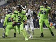 Seattle Seahawks quarterback Russell Wilson (3) scrambles before making a short pass to running back Chris Carson for a touchdown against the Los Angeles Rams during the second half of an NFL football game Thursday, Oct. 3, 2019, in Seattle.