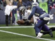 Baltimore Ravens quarterback Lamar Jackson (8) is hit by Seattle Seahawks cornerback Tre Flowers while scoring a touchdown on a fourth-down keeper play during the second half of an NFL football game, Sunday, Oct. 20, 2019, in Seattle.