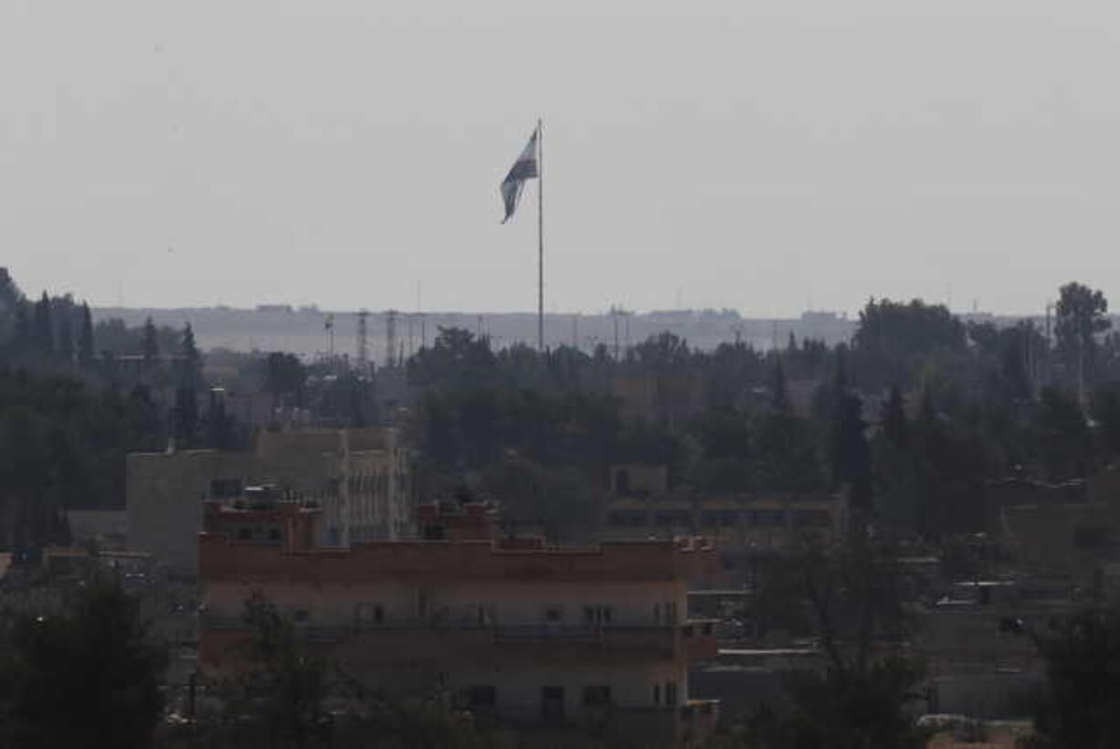 In this photo taken from the Turkish side of the border between Turkey and Syria, in Akcakale, Sanliurfa province, southeastern Turkey, Syria's opposition flag flies on a pole in Tal Abyad, Syria, Wednesday, Oct. 23, 2019. Russian media reports say Russian military police have started patrols in northern Syria as a Turkish-Russian agreement giving Syrian Kurdish fighters 150 hours to withdraw from almost the entire northeast border region of Syria came into effect.