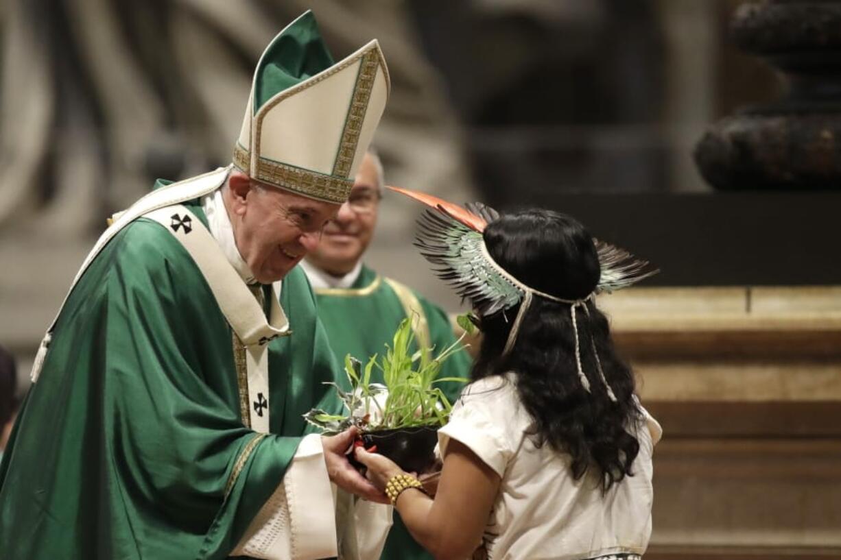 An Amazon indigenous girl gives Pope Francis a plant Sunday during the offertory of a Mass for the closing of Amazon synod in St. Peter&#039;s Basilica at the Vatican.