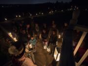 Volunteer Reggie Coats, bottom in hat, speaks to a group about to begin a lantern tour while other visitors make their way around the Fort Vancouver National Historic Site with their lanterns, one evening in October 2017.