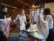 Seth Alcott, left, and his wife, Noelle Alcott, of Vancouver decide on a Turkish towel with the help of Elif Sari Genc, right, the owner of Hands on Hips, a Turkish towels and textiles shop, at the Night Market Vancouver last year.