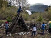 Ridgefield High School senior Tyson Ainsworth puts a rain poncho onto his group&#039;s shelter during a shelter-building exercise at the Cispus Learning Center. Ainsworth explained to the Sunset Ridge Intermediate School fifth graders that putting something noticeable like plastic or an item of clothing on top of your shelter can help draw attention to your location if a rescue helicopter is flying above you.